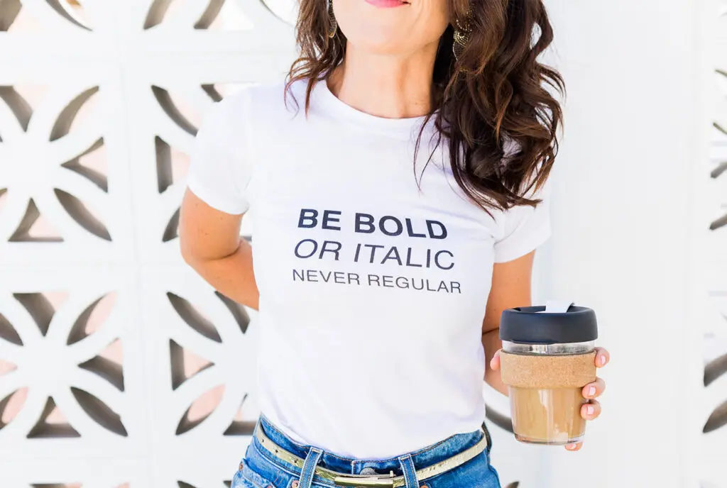 Female business owner wearing a white tshirt with the words be bold or italic never regular